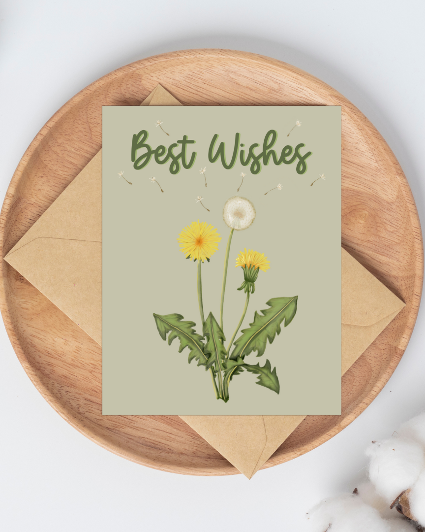A greeting card with an illustration of dandelions and the words Best Wishes on a light green background laying on a kraft envelope on a wooden plate