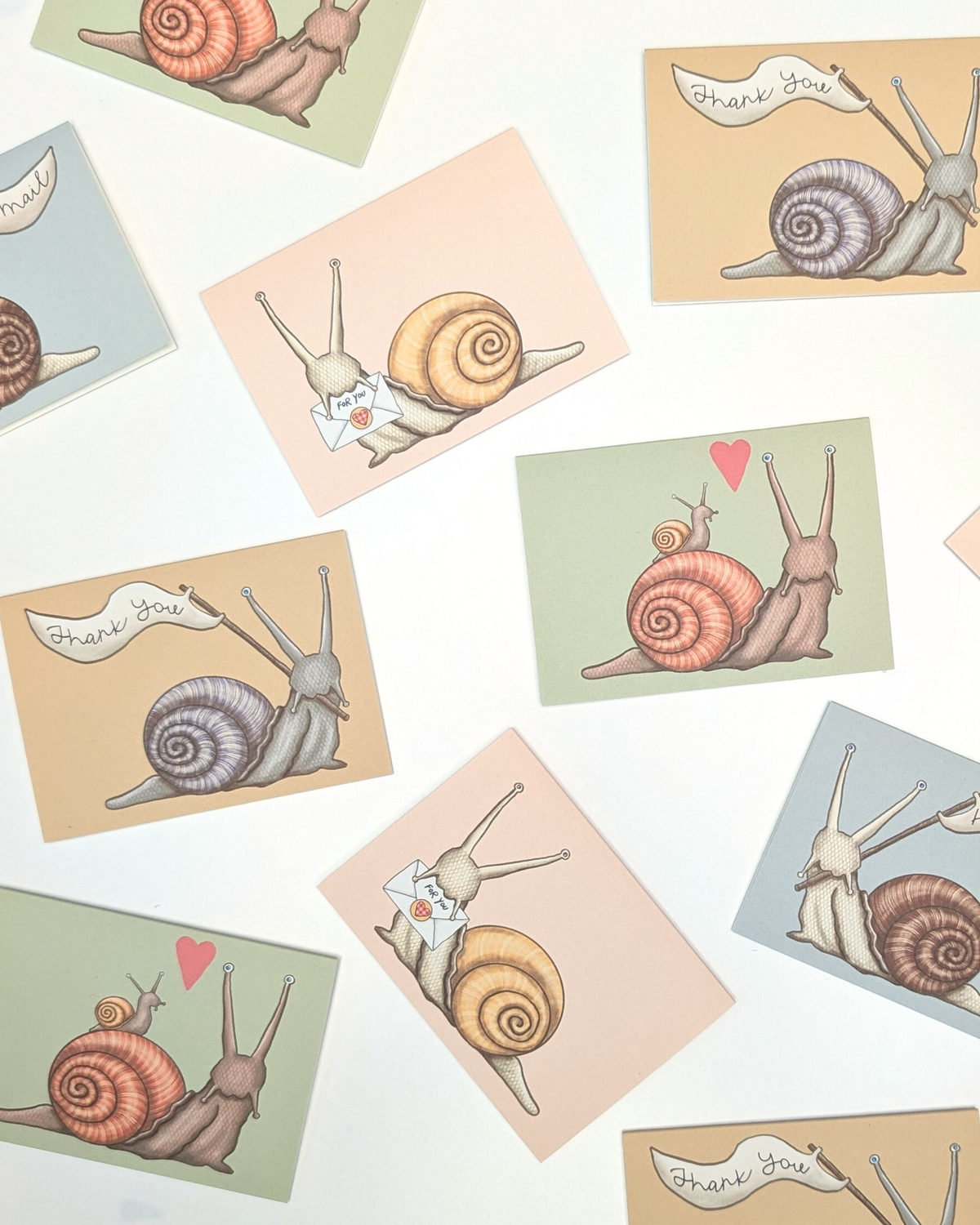 An assortment of mini enclosure cards with hand-drawn illustrations of snails on a white background