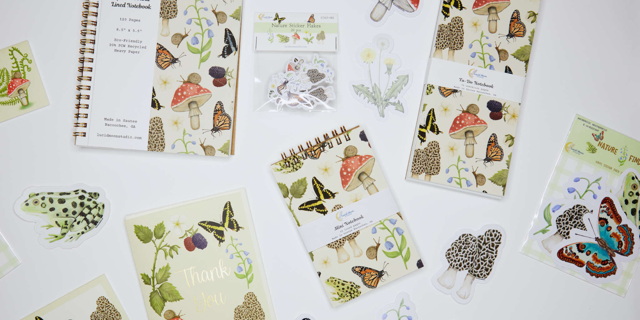 Collection of notebooks and stickers with nature-themed designs on a white surface