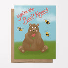 Adorable Valentine's greeting card featuring a cute bear surrounded by buzzing bees with the caption "You're the Bees Knees."