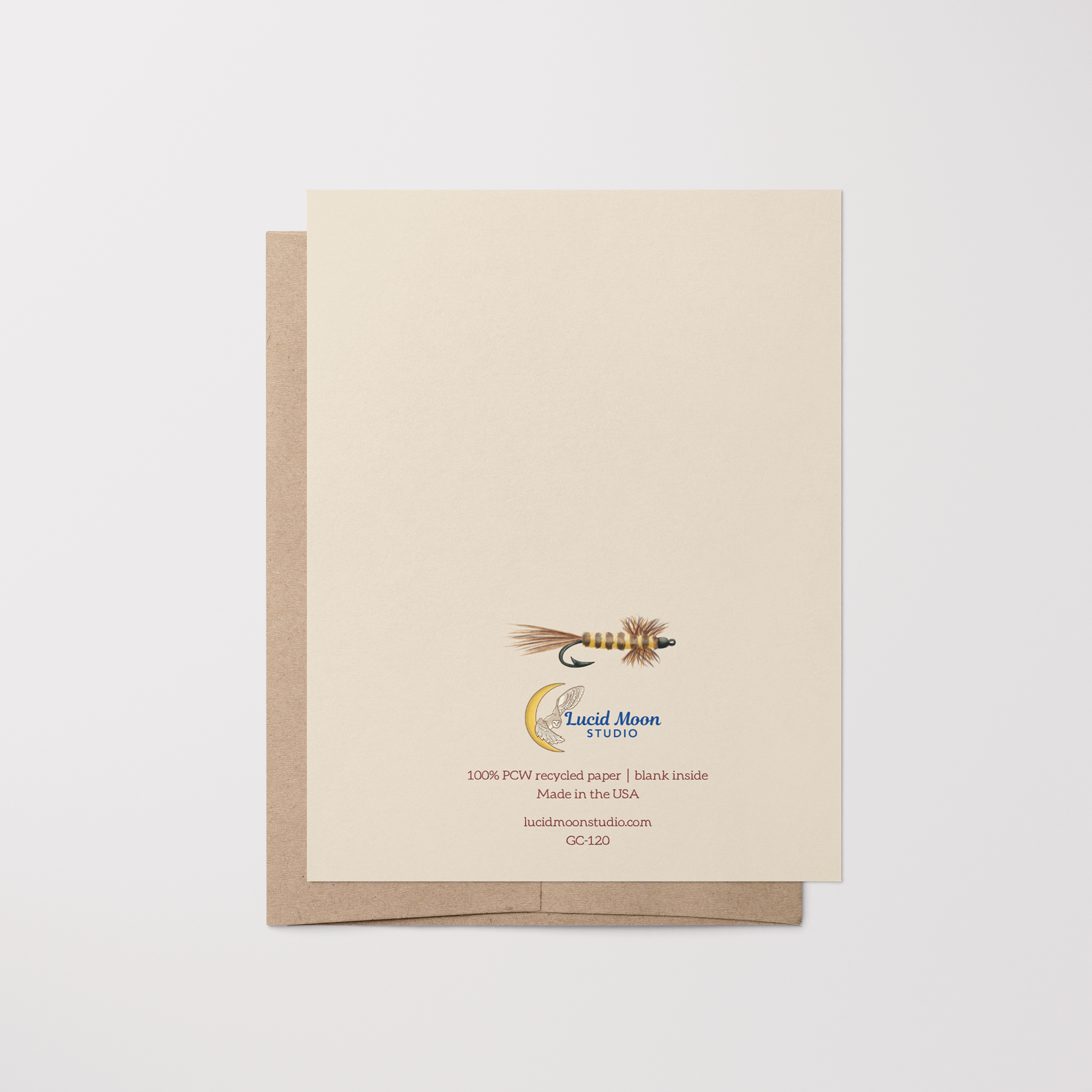 Back of greeting card with a brown and yellow fishing fly illustration, Lucid Moon Studio logo, website, and card information on top of a brown kraft envelope.