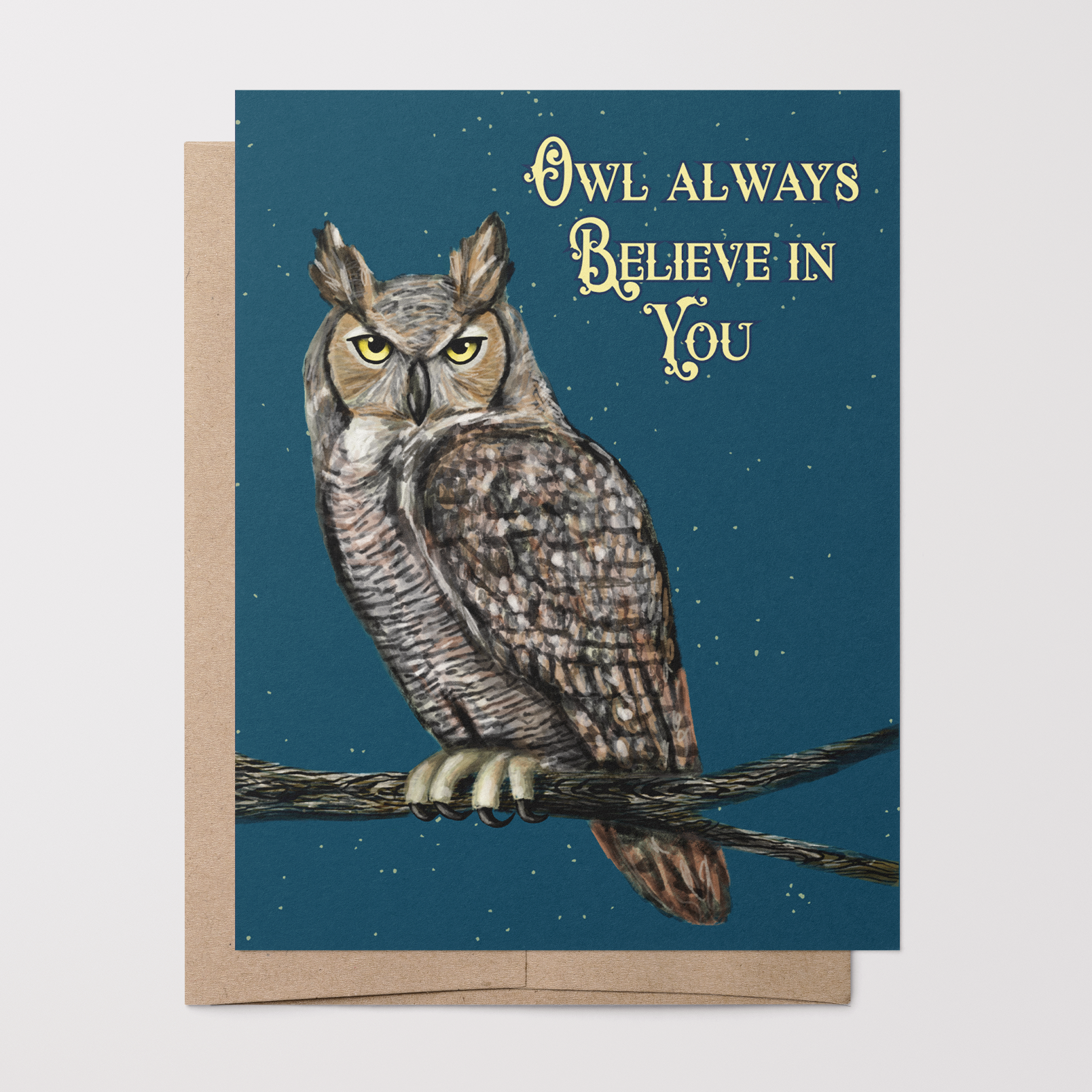 Greeting card with a painted Great Horned owl on a branch illustration on a dark blue background with stars on top of a brown kraft envelope.