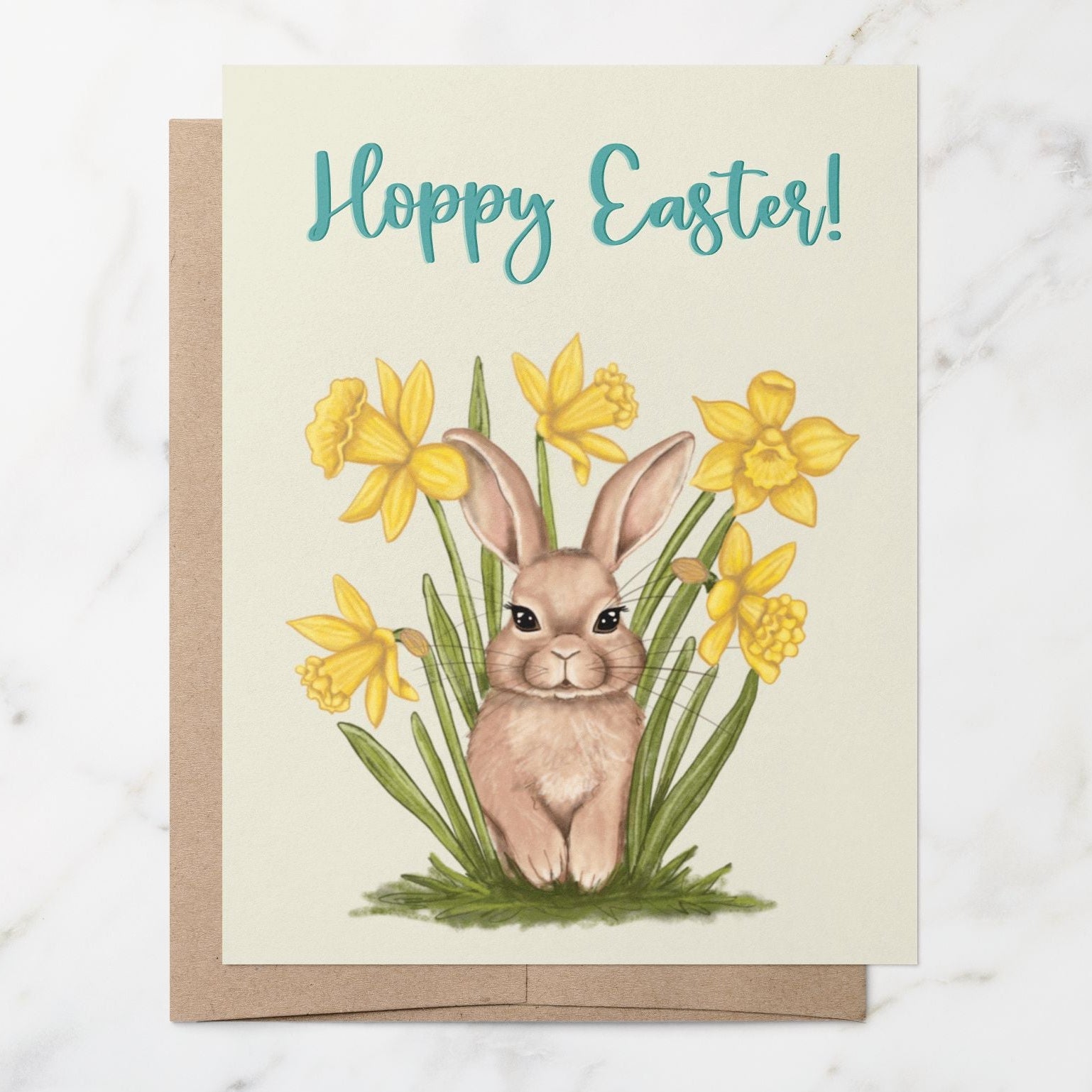 Easter card with a brown bunny and daffodils with the words "Hoppy Easter!" on a light yellow background on top of a brown kraft envelope.