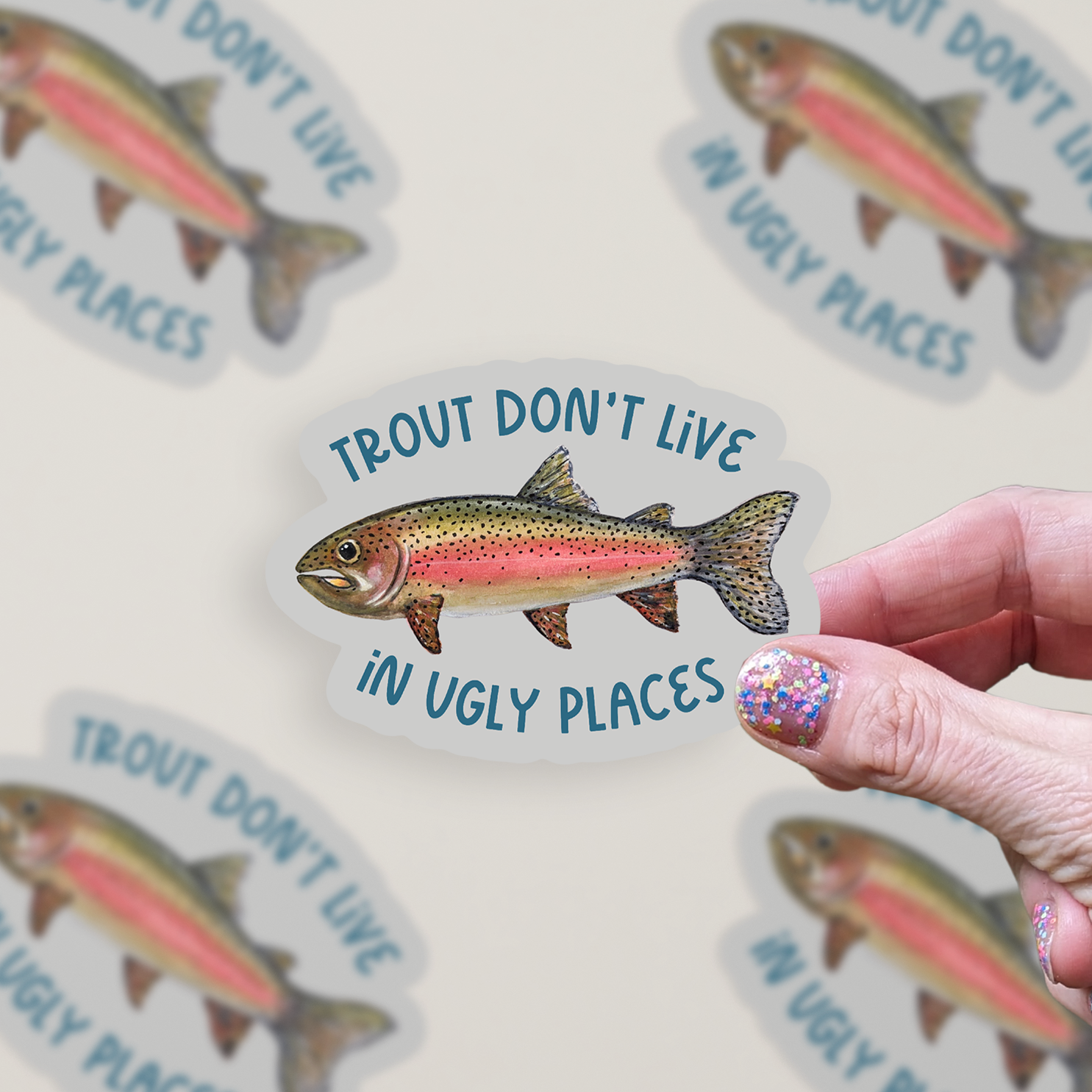 Die cut sticker with a watercolor rainbow trout illustration and the text "Trout don't live in ugly places" on a grey background