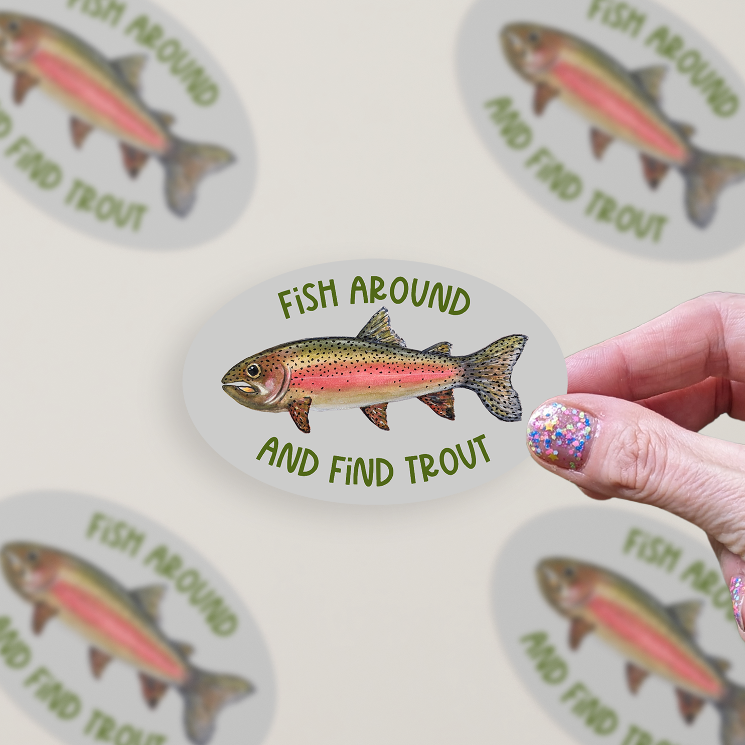 Oval-shaped sticker with a watercolor rainbow trout illustration and green text "Fish Around and Find Trout" on a grey background