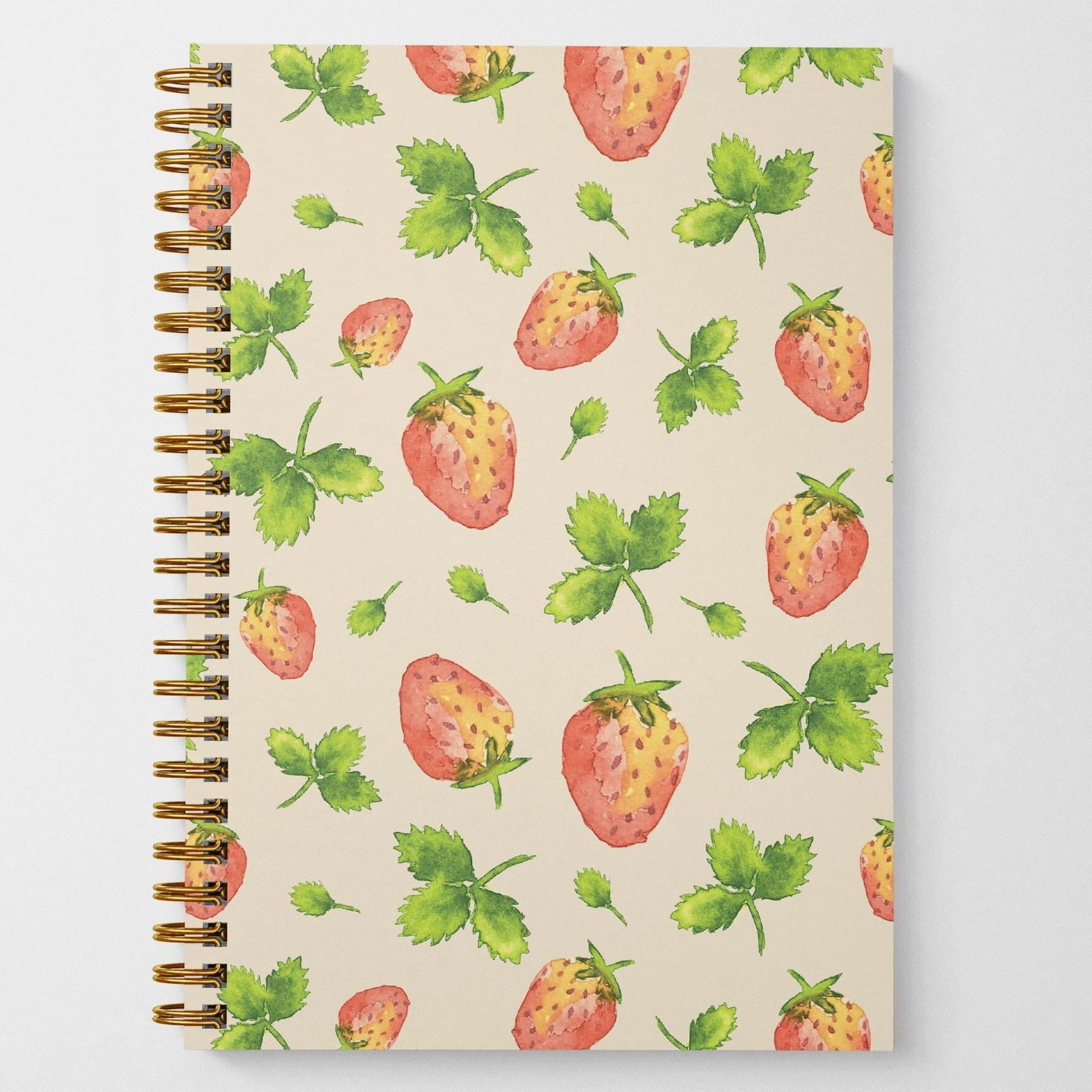 A photo of the front cover of a wire spiral-bound notebook featuring watercolor-painted strawberries and leaves in a tossed pattern.