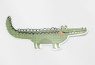 A glossy vinyl die cut sticker with a hand drawn illustration of a cute green crocodile.