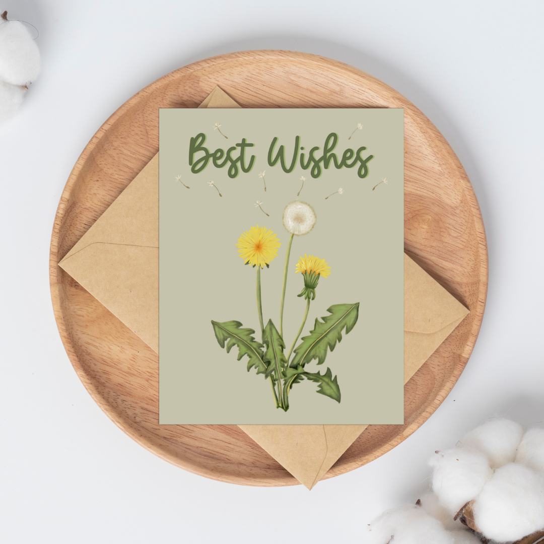 A greeting card with an illustration of dandelions and the words Best Wishes on a light green background laying on a kraft envelope on a wooden plate