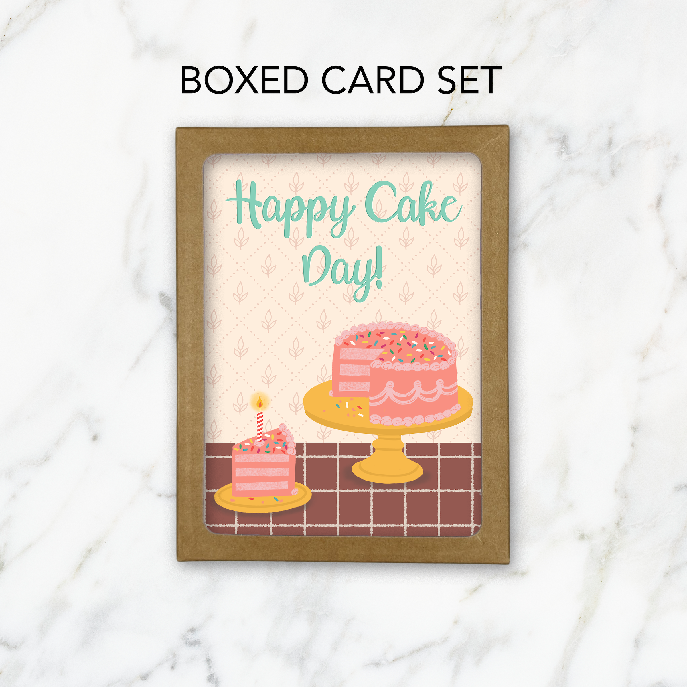 A kraft box with a cutout window showing greeting cards with a birthday cake illustration and the words Happy Cake Day! on a marble background