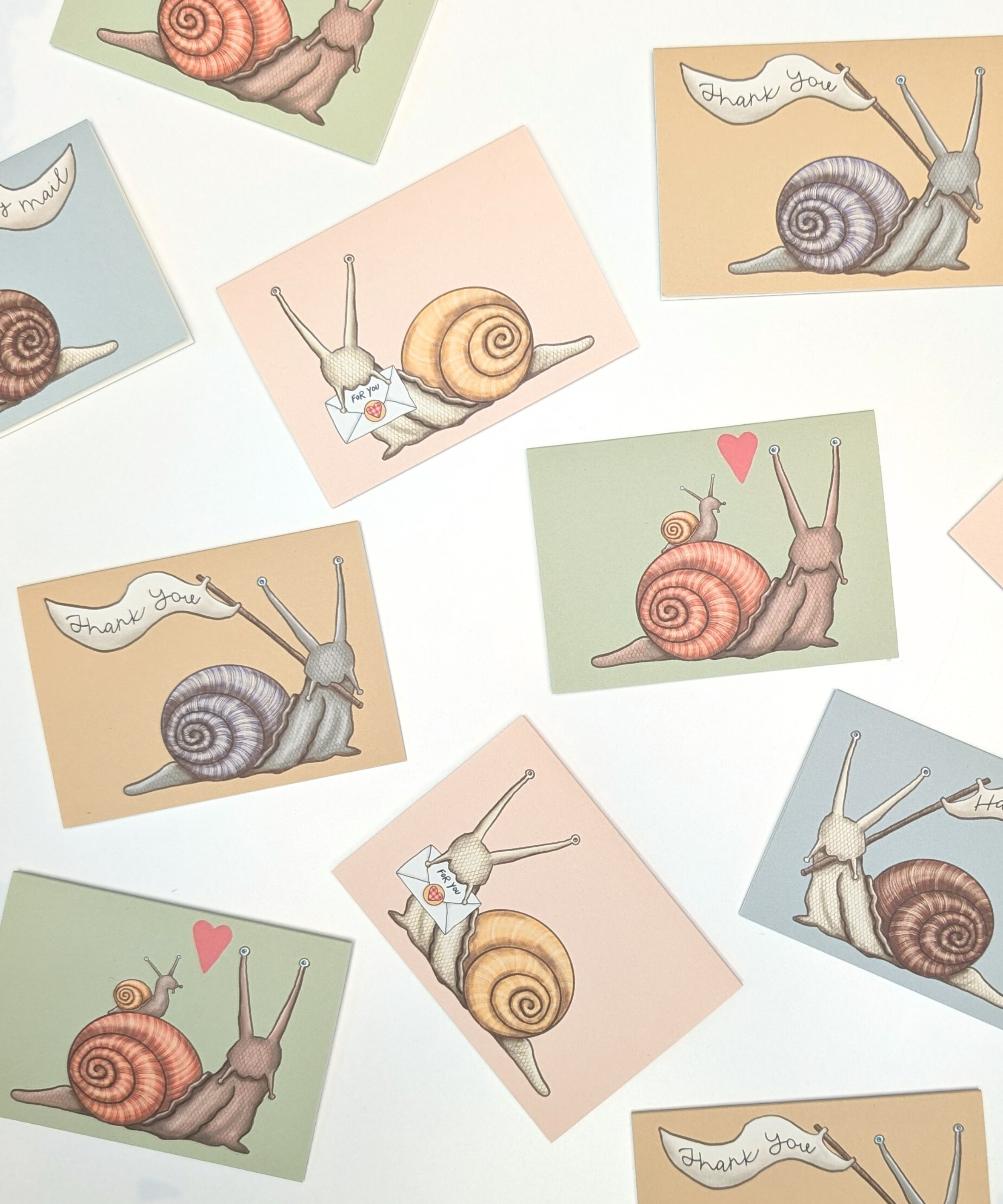 An assortment of mini enclosure cards with hand-drawn illustrations of snails on a white background