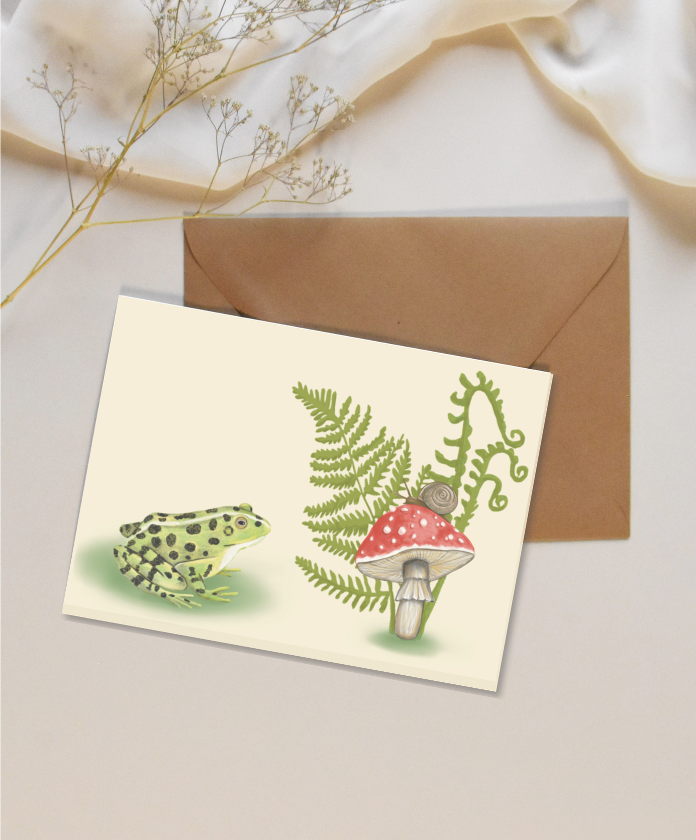 Blank mini card featuring a frog, fern, and mushroom on a tan background with a brown kraft envelope.