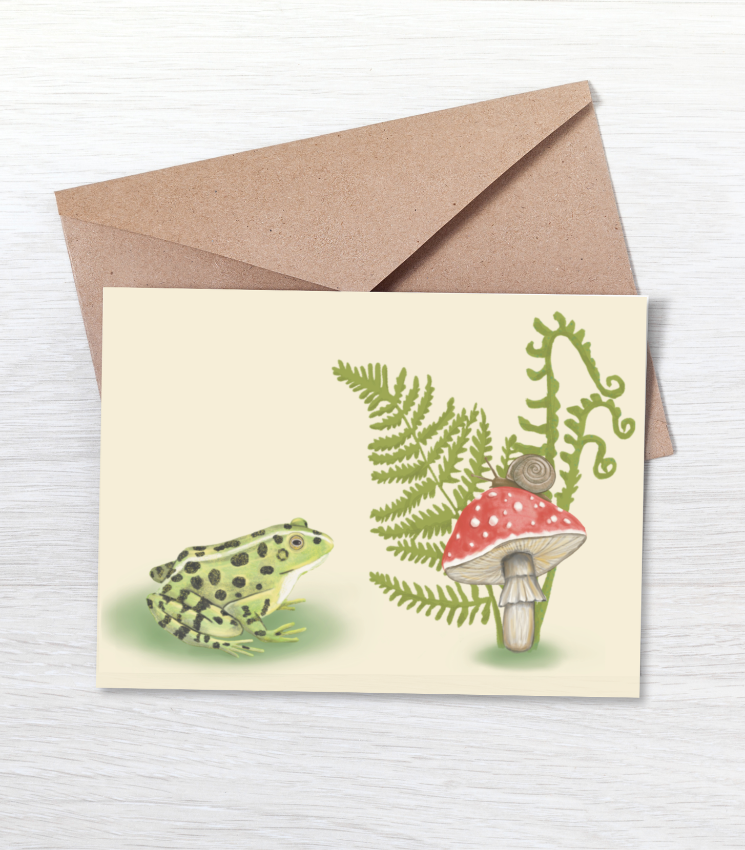 Blank mini card featuring a frog, fern, and mushroom on a tan background with a brown kraft envelope.