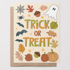 Halloween-themed greeting card with 'Trick or Treat' text and autumnal and Halloween motifs such as bats, spiders, ghost, pumpkins, fall leaves, acorns on a beige background with a brown kraft envelope.