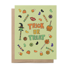 A Halloween greeting card with a light sage green background and 'TRICK OR TREAT' text in orange and green, surrounded by small candy and pumpkin illustrations. A kraft paper envelope is placed behind the card on a white background.