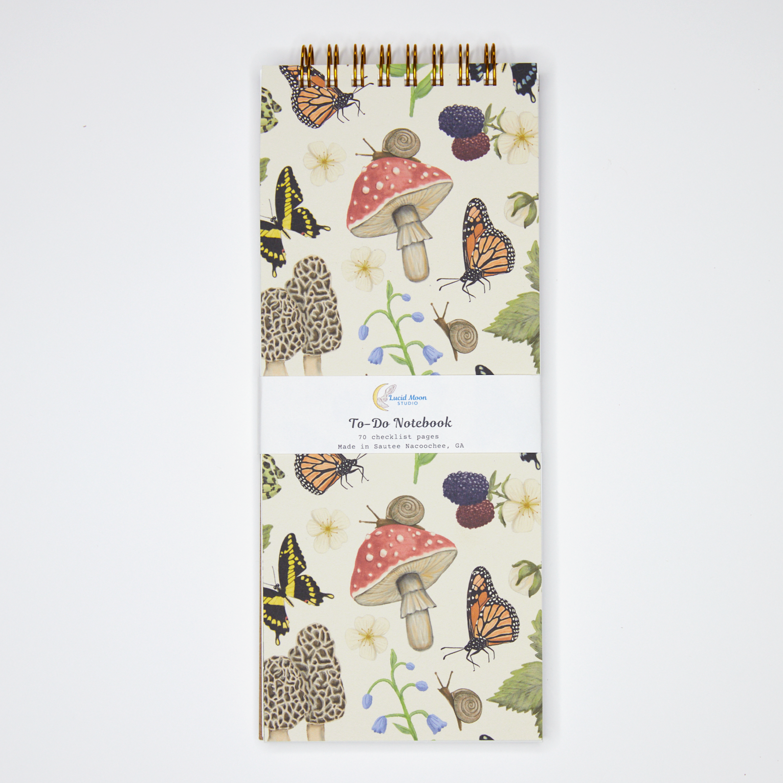 Notebook with nature-themed design featuring mushrooms, butterflies, and flowers on a white background.