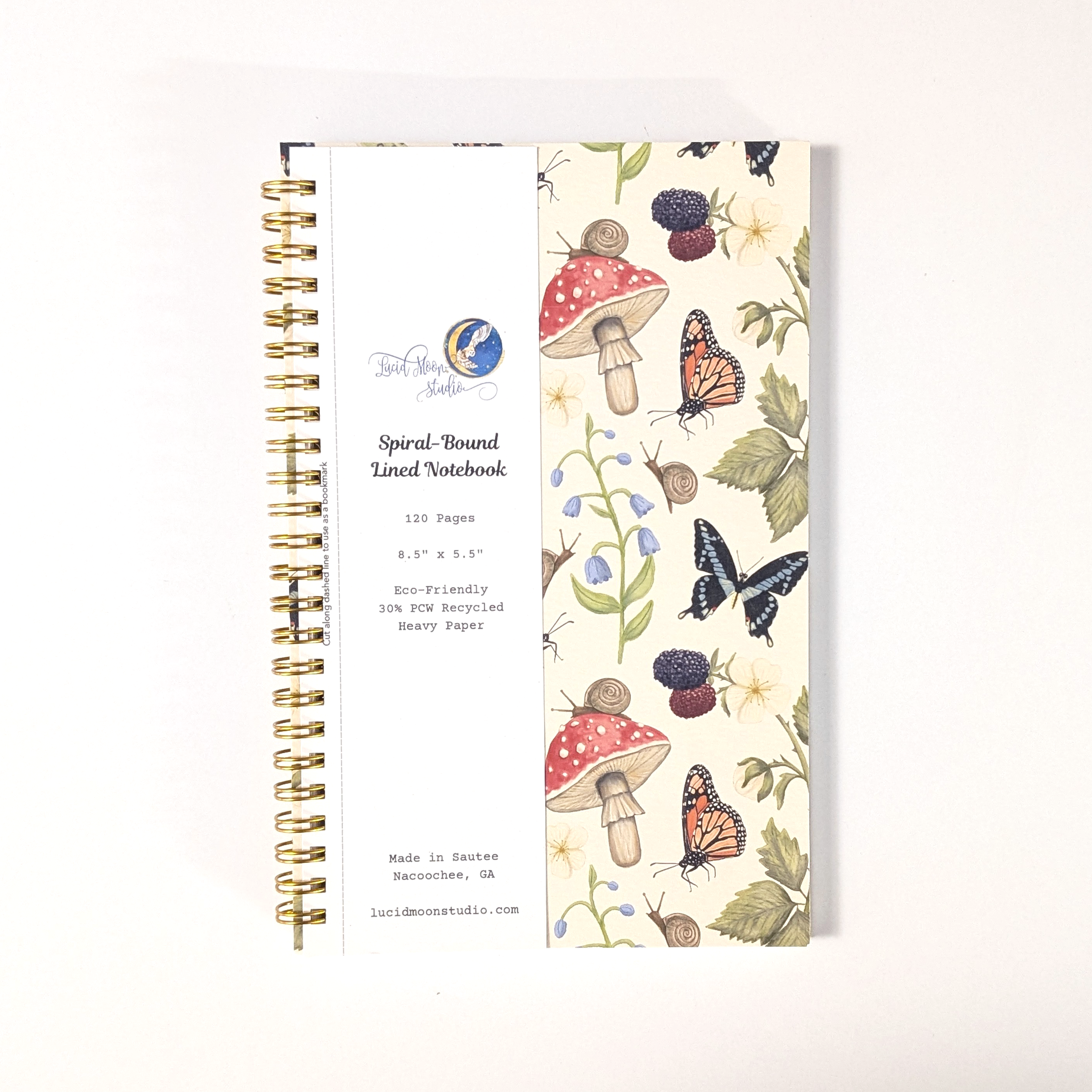 Notebook with nature-themed design including butterflies, mushrooms, snails, berries, and frogs on a white background