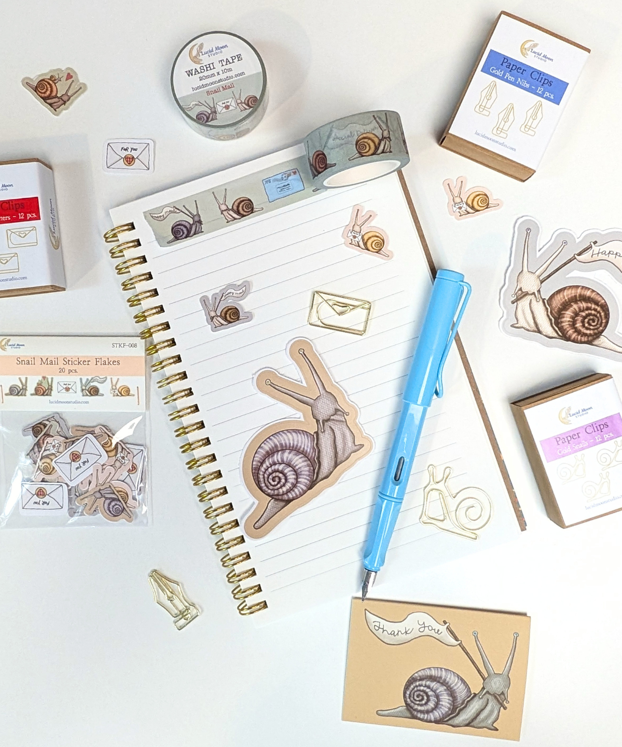 An assortment of snail mail themed stationery products that include stickers, washi tape, shaped paper clips, and mini cards