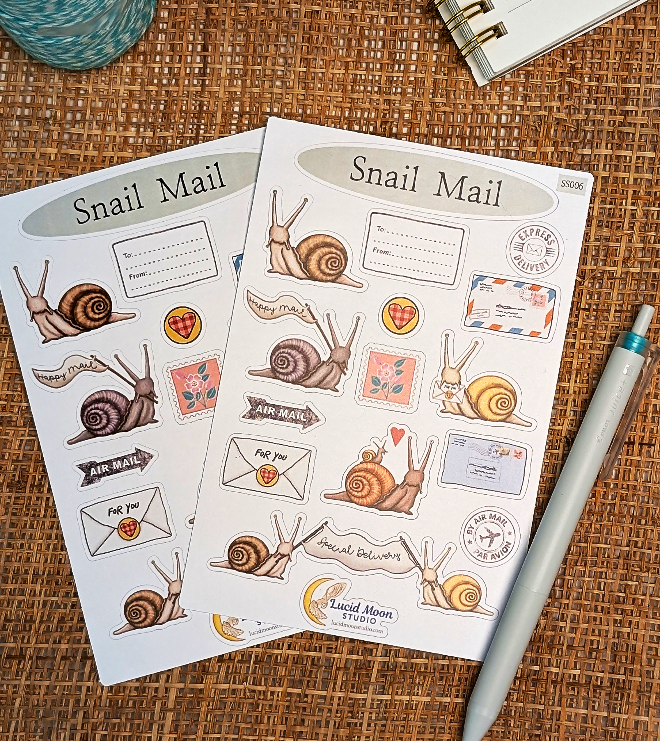 Two sheets of 'Snail Mail' themed stickers on a textured surface with a pen.