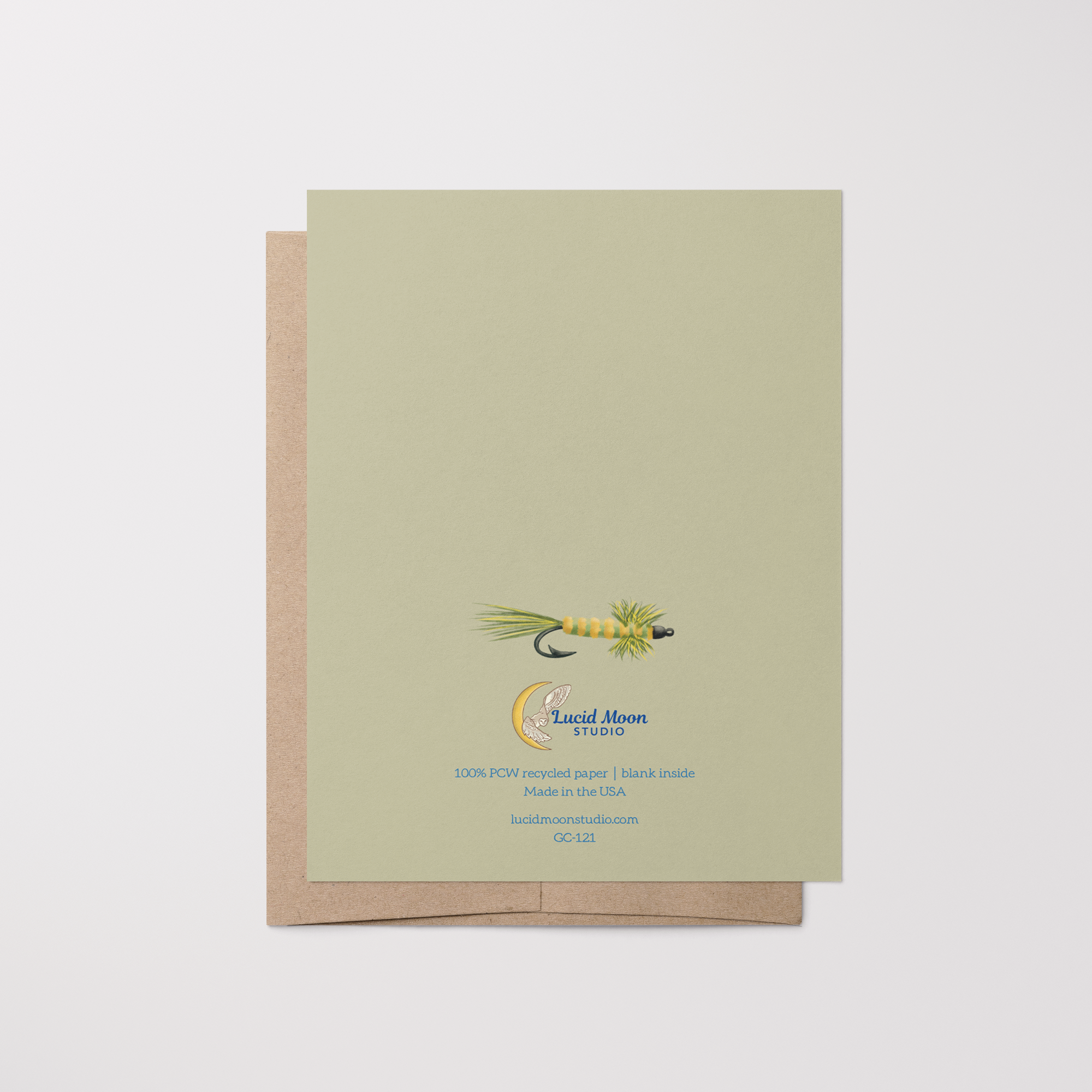 Back of greeting card with an illustration of a green and yellow fishing fly lure, Lucid Moon Studio logo, website, and card information on a light green background on top of a brown kraft envelope.