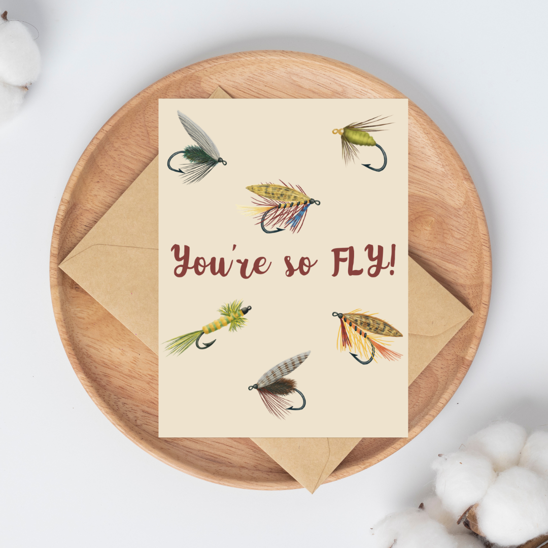 Love/friendship card with 6 fishing fly illustrations and text "You're so FLY!" on a tan background on top of a brown kraft envelope.