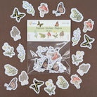 A set of nature-themed sticker decals arranged around a clear plastic bag containing the remaining stickers, with a label card reading 'Nature Sticker Decals' on a brown background.