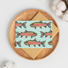 Greeting card with a school of watercolor rainbow trout illustrations on a mint green wavy pattern background with a brown kraft envelope.