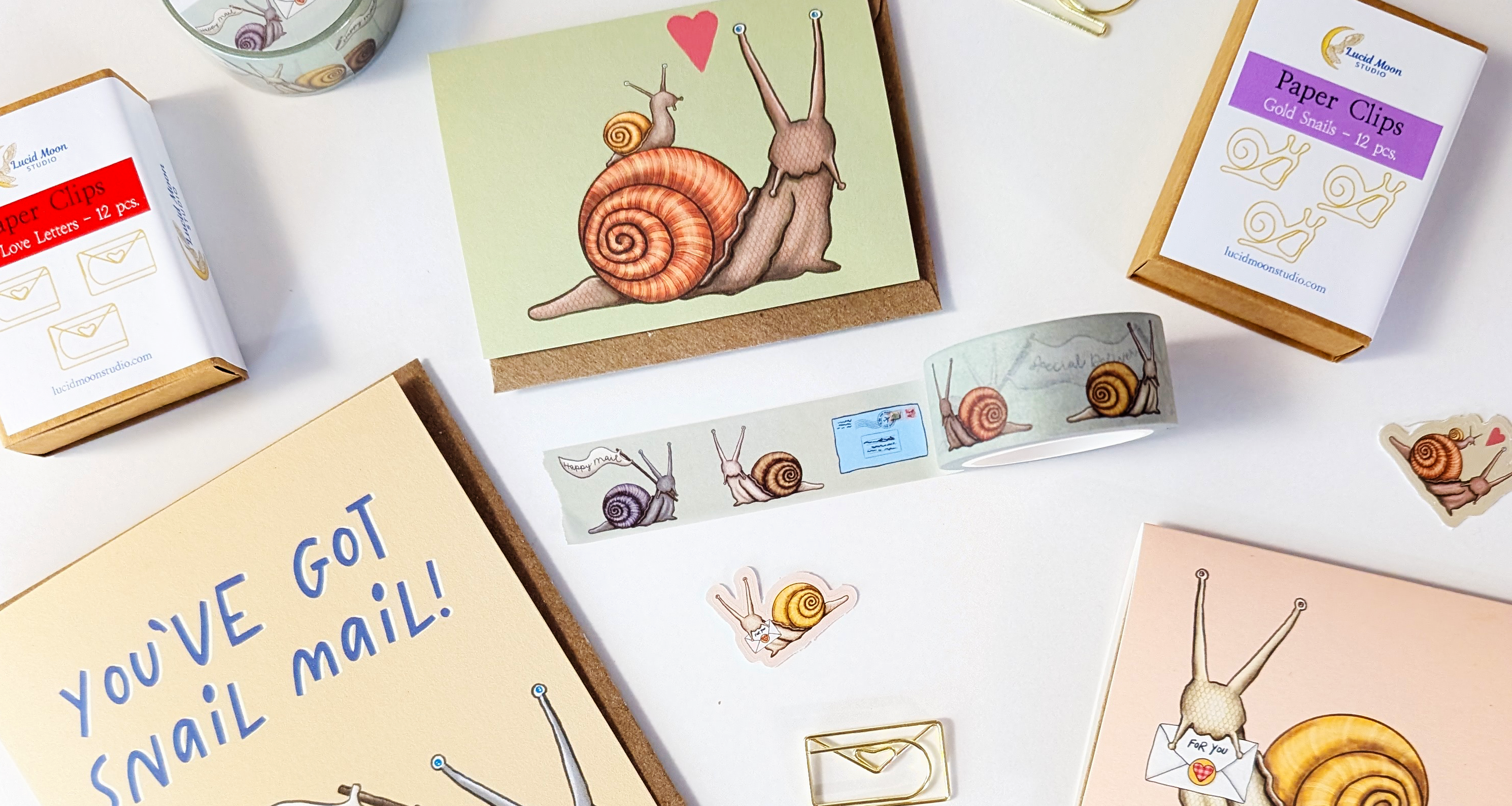 An assortment of snail mail themed stationery that includes cards, stickers, washi tape, and snail paper clips